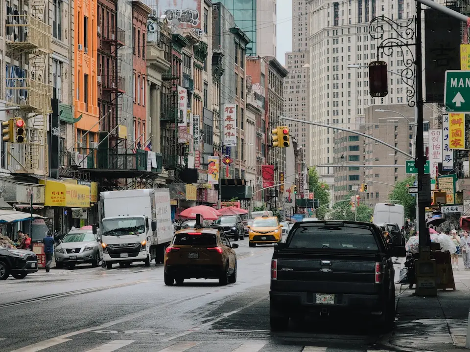 A street in Chinatown with a few cars in the center